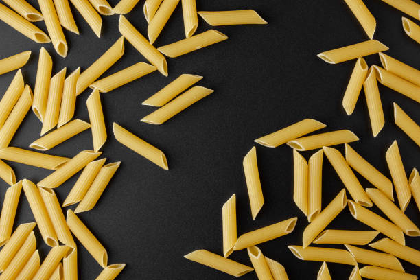 istock Raw pasta penne rigate with copy space on black background. 1417561799