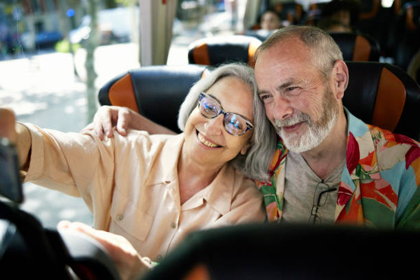 pensionierte senioren, die ein selfie an bord des charterbusses machen - front view bus photography day stock-fotos und bilder