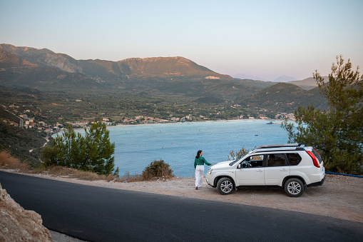 car travel concept. woman standing at the cliff looking at sea bay Lefkada Greece