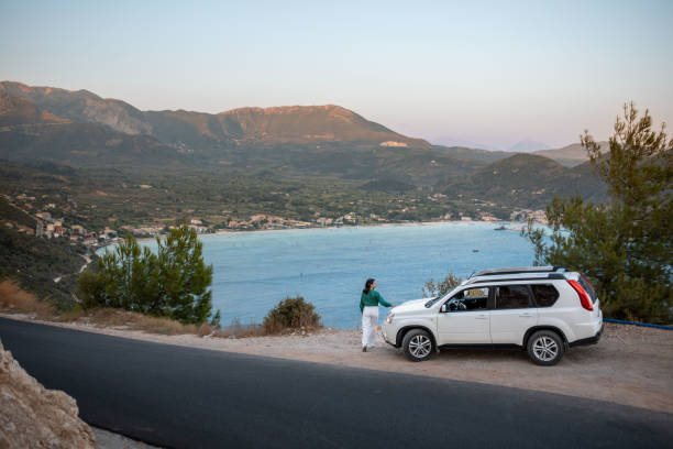 car travel concept. woman standing at the cliff looking at sea bay stock photo