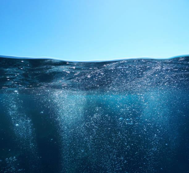 Air bubbles underwater sea and blue sky over under water surface stock photo