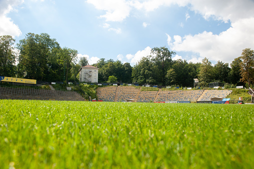 This photo is of an American Football Field at Football Game. the football field shows the sidelines and each yard-line of the football field. the lawn is green grass or artificial turf. the lighting is natural sunlight during the day. 