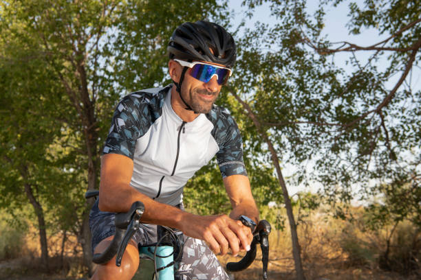 istock Triathlon athlete leaning on the handlebars smiling with helmet and sunglasses. Security 1417567302