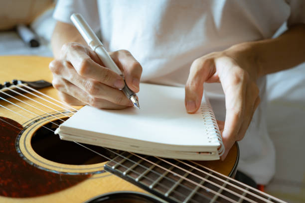 musicien utilisant un stylo et un cahier pour écrire une chanson - lyricist photos et images de collection