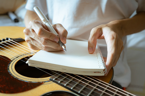 Musician using pen and notebook to write a song