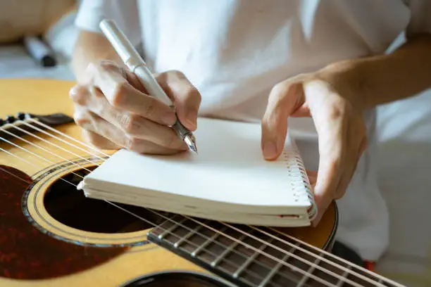 Musician using pen and notebook to write a song