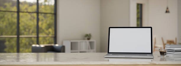istock Marble workspace tabletop with laptop mockup and copy space over blurred white living room 1417574441