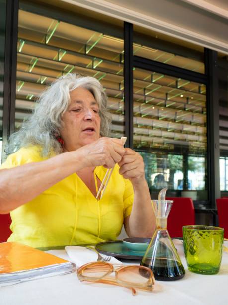 istock senior woman using bamboo sticks at the table asian restaurant 1417574614