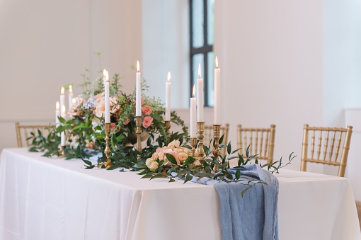 A wedding-style tablescape with a blue runner and elegant lit candles