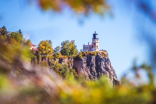 Split Rock Lighthouse in Minnesota framed by autumn leaves.