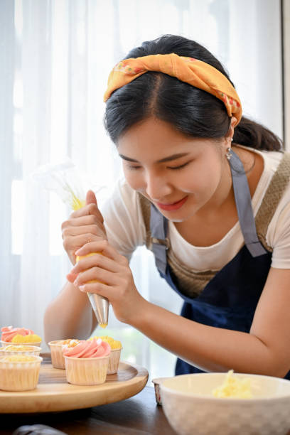 istock Woman using cream squeeze bag to decorating the cupcake, making cupcake 1417579672