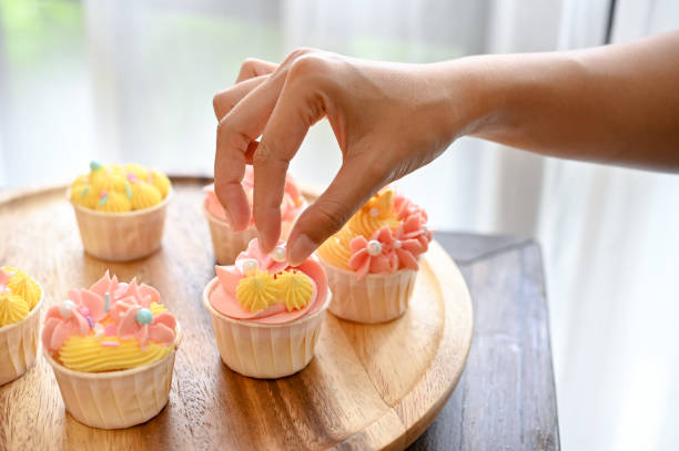 istock A female baker decorating her beautiful homemade cupcake with tiny white chocolate ball. 1417579815