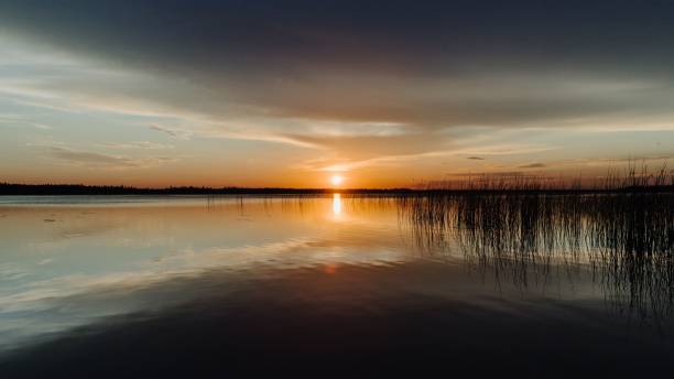 un coucher de soleil se reflétant à l’horizon à candle lake, dans le nord de la saskatchewan, au canada - northern lake photos et images de collection