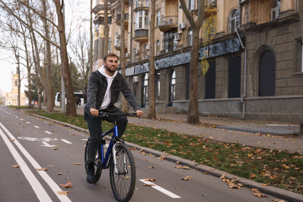 счастливый красавец едет на велосипеде по дорожке в городе - single lane road стоковые фото и изображения