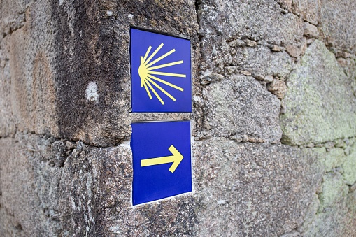 Camino de Santiago sign tiles on stone wall. Way of St. James symbol. Pilgrimage to Santiago de Compostela
