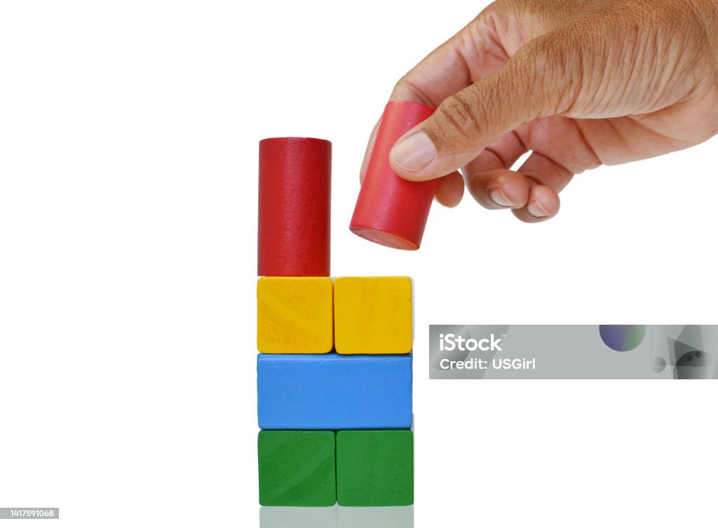 Building Blocks Close up of hand placing cylinder shaped wooden block on top of a yellow one Cylinder Stock Photo