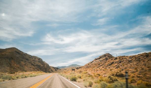 istock Asphalt road through hills and plants under blue cloudy sky 1417591631