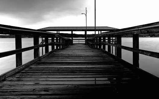 An isolated wooden bridge on a lake in grayscale