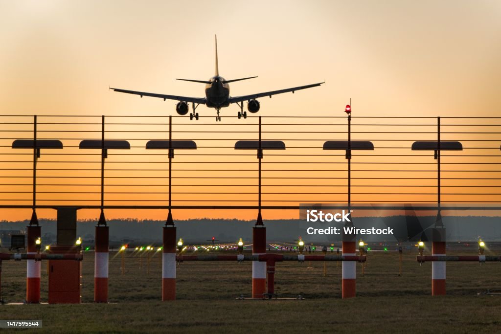 Landing plane at stuttgart airport at sunset A photo of a landing plane at Stuttgart airport at sunset Agricultural Field Stock Photo
