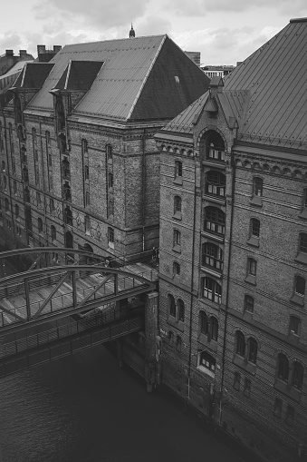 A grayscale vertical shot of the multi-storey buildings with entrances from water and land. Speicherstadt, Hamburg, Germany