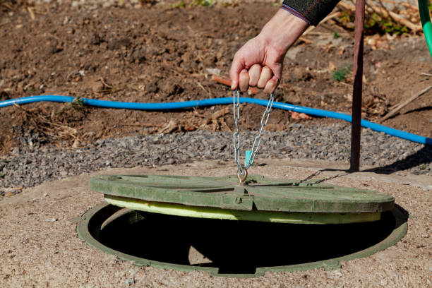 Hand opens sewer hatch in yard stock photo