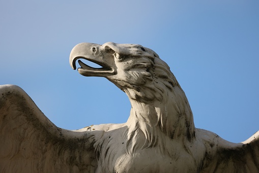 A closeup shot of a beautiful stone sculpture of an eagle under the blue sky