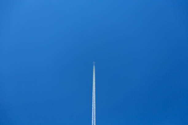 eine überkopfansicht eines flugzeugs, das über einen blauen himmel fliegt und einen weißen kondensstreifen hinter sich lässt. - aerial passenger line stock-fotos und bilder