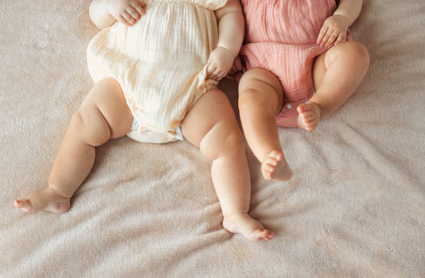 nessuna faccia due bambine gemelle attive sdraiate sul letto - twin newborn baby baby girls foto e immagini stock