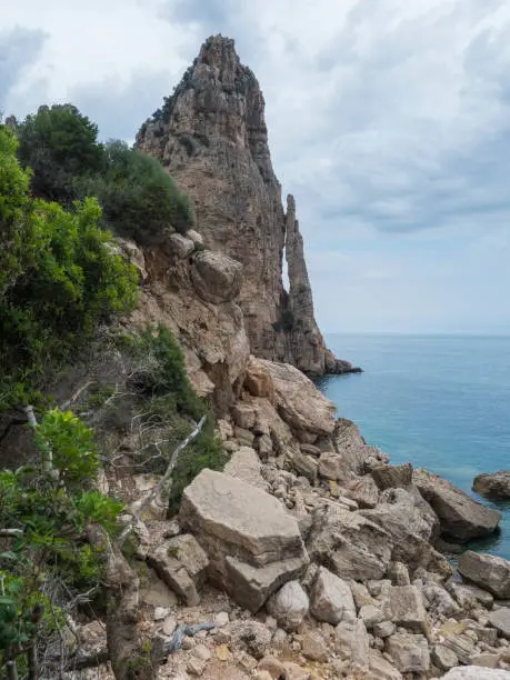 Photo of View of Pedra Longa, limestone rock pillar at coast Gulf of Orosei, beginning of the famous and difficult hiking climbing trail Selvaggio blu, wild blue, Sardinia, Italy