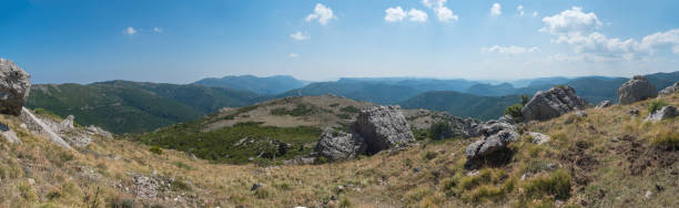 Panoramic view from white limestone tower Perda Liana, impressive rock boulders, green forest hill and mountain. National Park of Barbagia, Central Sardinia, Italy, summer day