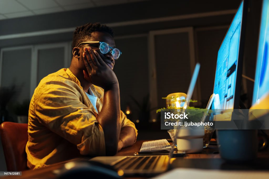 Bored male programmer working on PC in the office. Computer Programmer Stock Photo
