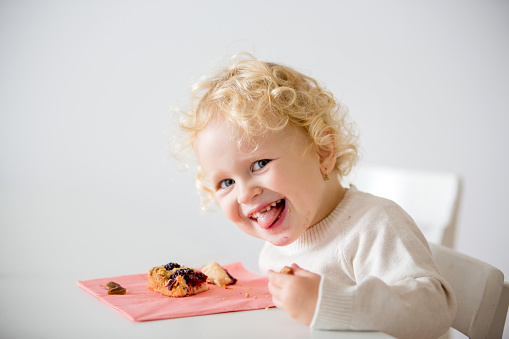 Cute little toddler child, eating homemade plum pie at home, tasty pastry desert