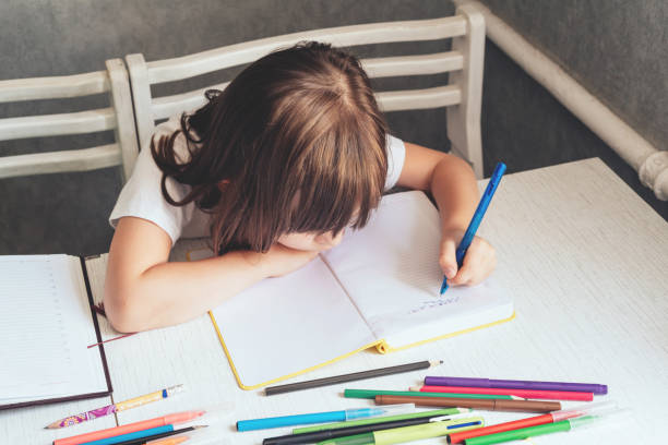 Girl sitting at the table and writing in a notebook
