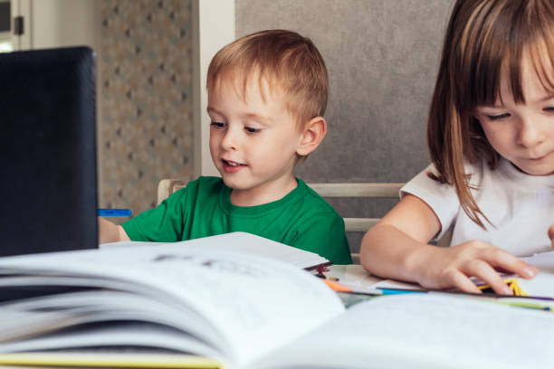 istock Child sits at the table, uses a laptop and writes in a notebook 1417614538