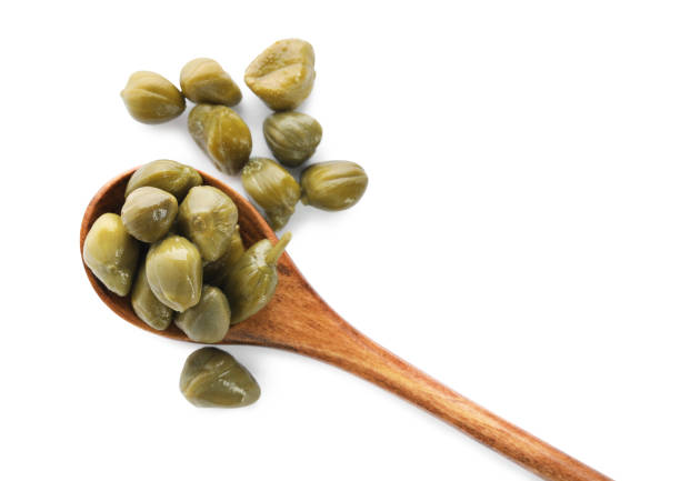 Wooden spoon and capers on white background, top view Wooden spoon and capers on white background, top view caper stock pictures, royalty-free photos & images