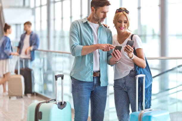 istock Man sharing smart phone with girlfriend at airport 1417617555
