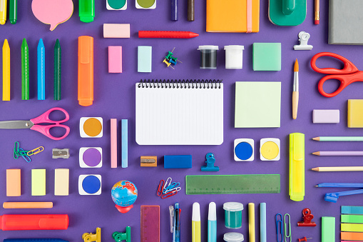 Large group of school supplies on purple background