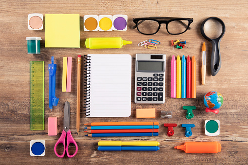 Directly above view of a large group of school supplies on brown wooden table