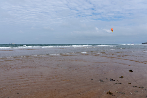 Kite boarding at Seaton Sluice beach, Seaton Sluice, Northumberland, England, UK. In the background is Rocky Island.