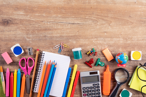 Directly above view of a large group of school supplies on brown wooden table