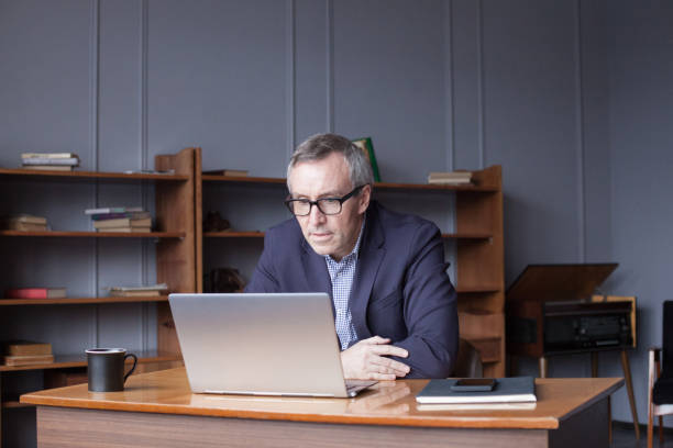 istock Mature man using laptop at home 1417619905