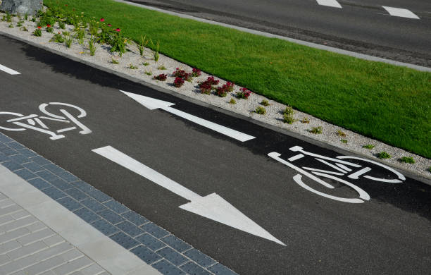 promenade for pedestrians and cyclists with a dividing island between the lanes and road, road markings sprayed with paint on asphalt. wheel, arrow and triangle traffic sign pictogram. luxury spa promenade for pedestrians and cyclists with a dividing island between the lanes and road, road markings sprayed with paint on asphalt. wheel, arrow and triangle traffic sign pictogram. luxury spa, bergenia, cineraria maritima, farinacea, kochia, mulch cineraria maritima stock pictures, royalty-free photos & images