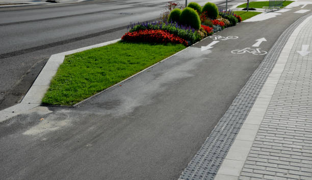 promenade for pedestrians and cyclists with a dividing island between the lanes and road, road markings sprayed with paint on asphalt. wheel, arrow and triangle traffic sign pictogram. luxury spa promenade for pedestrians and cyclists with a dividing island between the lanes and road, road markings sprayed with paint on asphalt. wheel, arrow and triangle traffic sign pictogram. luxury spa, bergenia, cineraria maritima, farinacea, kochia, mulch cineraria maritima stock pictures, royalty-free photos & images