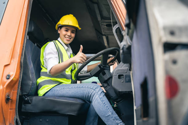 asian woman truck driver sitting in truck cabin looking at camera. - chauffeur beroep stockfoto's en -beelden