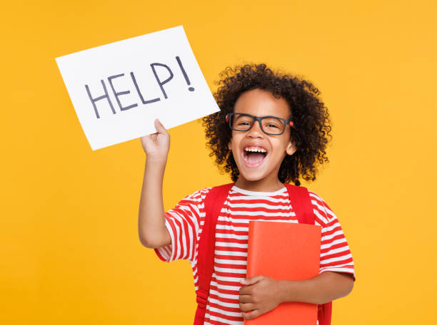 istock Happy ethnic schoolboy holds a sign HELP and book and laughs 1417628250