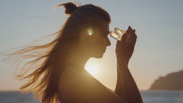 kobieta trzymająca kryształ o zachodzie słońca. kryształy lecznicze - mantra zdjęcia i obrazy z banku zdjęć