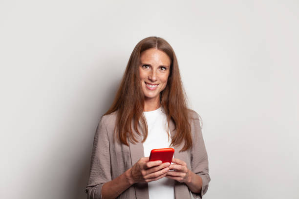istock Nice cheerful mature woman using smartphone on white background 1417635922