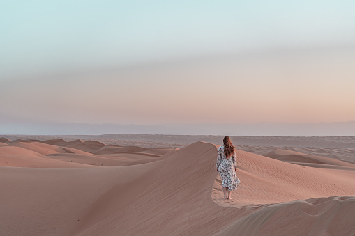 Woman is wandering around in the desert of Oman.