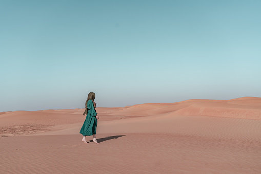 Woman is wandering around in the desert of Oman.