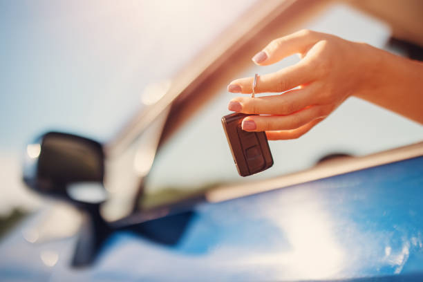 Woman's hand holding key from her new car stock photo